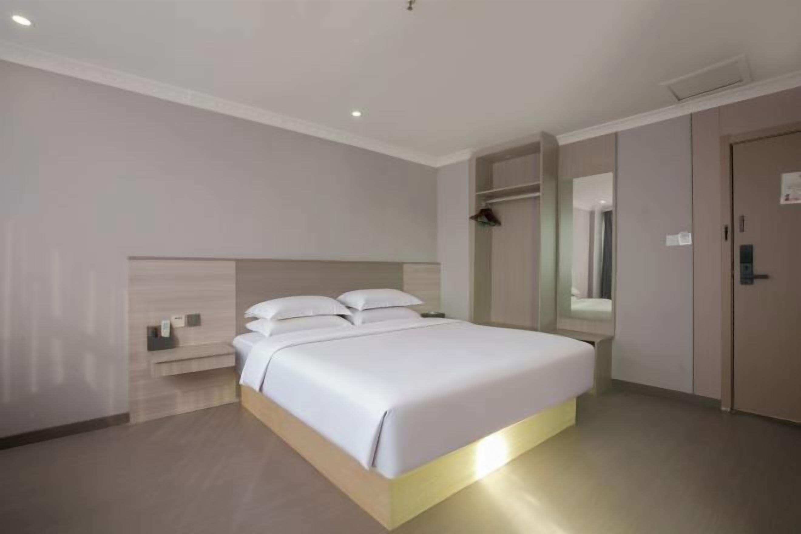 A hotel room with a bed, bedside table, and a wardrobe.