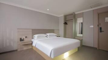 A hotel room with a bed, bedside table, and a wardrobe.