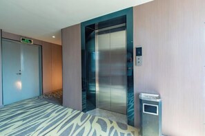 An elevator with a digital display, a trash bin, and a carpeted floor. - Huating Hotel (Zhuhai Youtehui Branch) (Zhuhai)