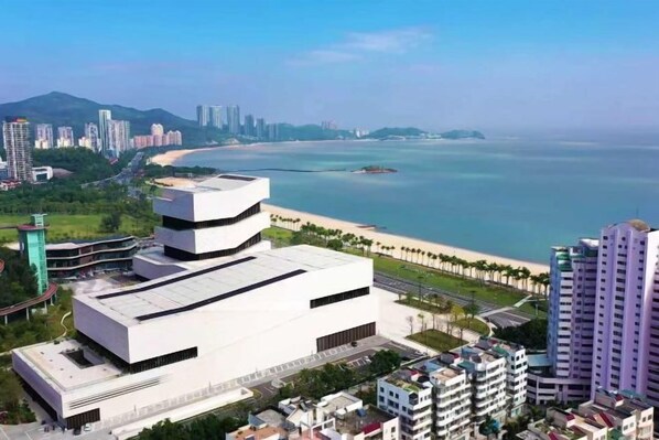 A coastal cityscape with modern buildings, a beach, and a marina.