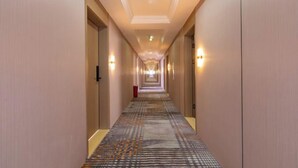 A hotel hallway with carpeted floors, doors on both sides, and wall-mounted lights. - Huating Hotel (Zhuhai Youtehui Branch) (Zhuhai)