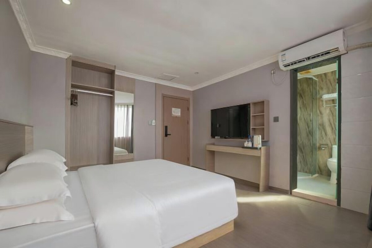Una habitación de hotel con cama, televisión, baño y armario.