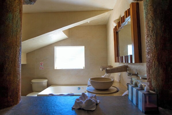 Une salle de bain avec une baignoire, un grand lavabo en forme de cuve, une fenêtre et un miroir.
