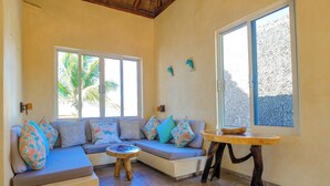 A cozy room with a sofa, a round wooden table, and large windows. - Right in front of the sea! Maguey House (La Manzanilla)