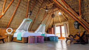 A room with a high thatched ceiling, a bed with mosquito nets, a fan, and a wooden chair. - Right in front of the sea! Maguey House (La Manzanilla)