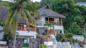 A two-story building with a thatched roof, stone walls, and a balcony with wooden railings. - Right in front of the sea! Maguey House (La Manzanilla)