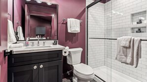 A modern bathroom with a vanity, a toilet, a shower area, and a glass-enclosed shower stall.