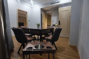 A dining area with a table and chairs, a small kitchen area, and a mirror on the wall. - Magnotel (Chongqing Jiefangbei Pedestrian Street store) (Chongqing)