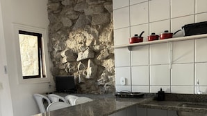 Eine Küche mit Steinwand, weißen Schränken und einer Arbeitsplatte aus Granit.