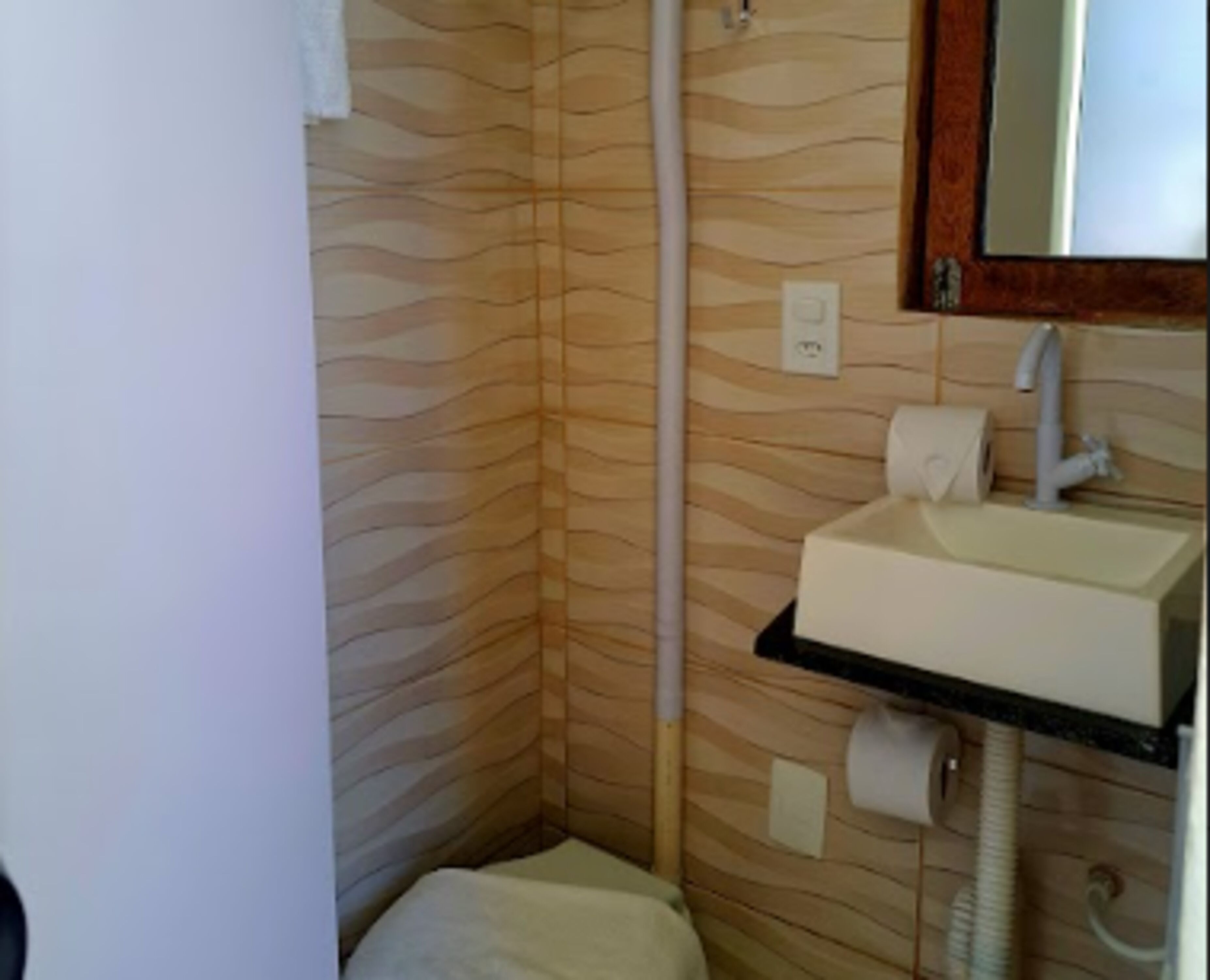 A bathroom with a wooden wall pattern, a white sink, a mirror, and a toilet.