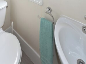 A bathroom with a toilet, a sink, and a towel hanging on a metal rack. - 2 bedroom accommodation in Thorness, near Cowes (Thorness, near Cowes)