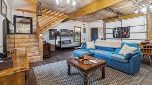 A cozy loft-style room with a bunk bed, a blue sofa, and a wooden desk. - Davy Jones' Loft, Treehouse, and Treasure Hunt! (Wilmington)