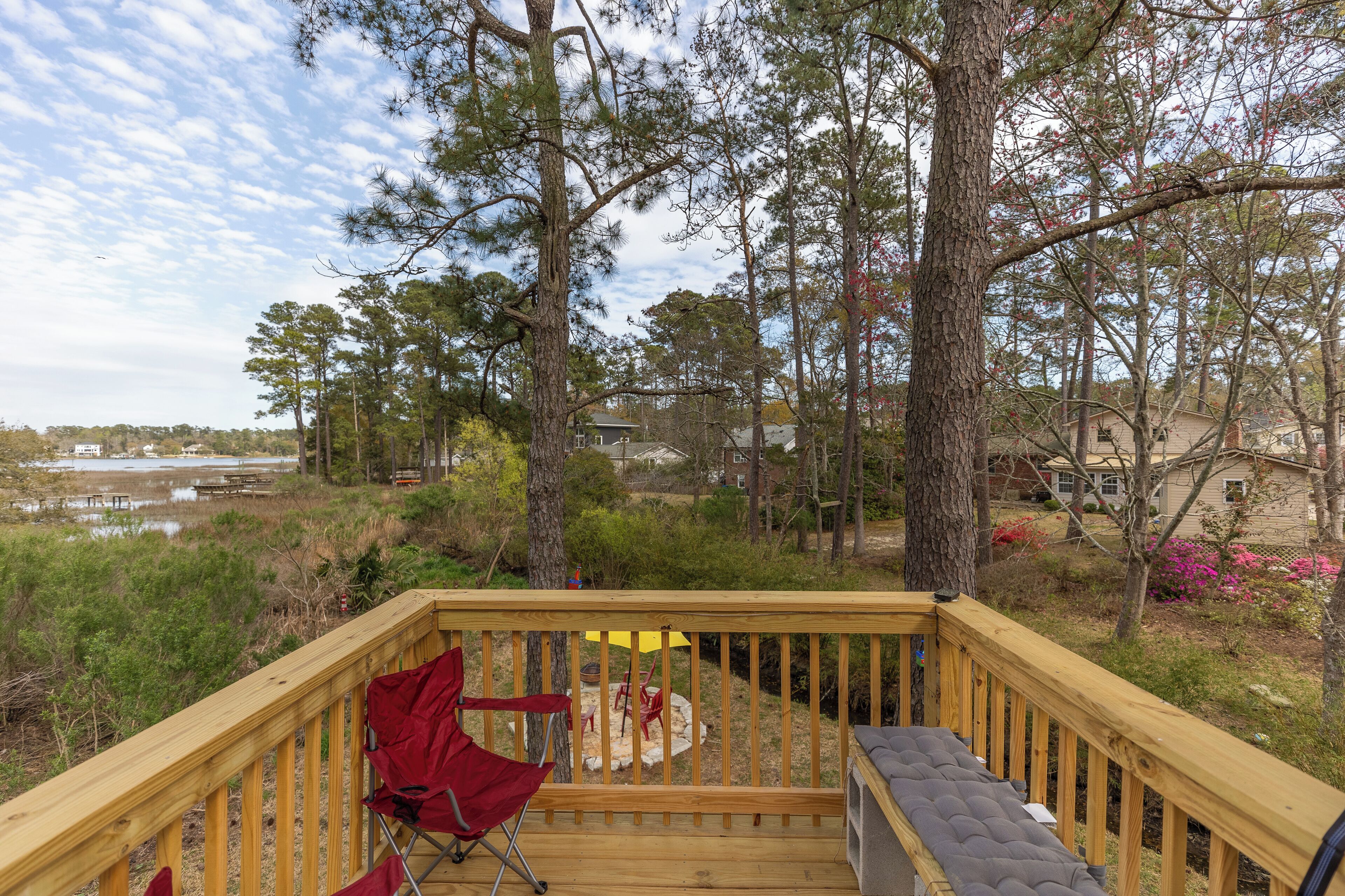 A wooden deck with a red folding chair and a grill.