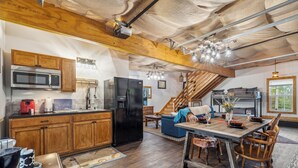 A spacious kitchen with wooden cabinets, a black refrigerator, and a dining area with a wooden table and chairs. - Davy Jones' Loft, Treehouse, and Treasure Hunt! (Wilmington)