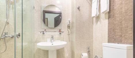 Ein modernes Badezimmer mit einer begehbaren Glasdusche, einem Standwaschbecken und einer Toilette.