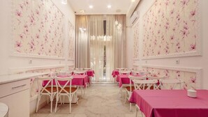 A dining area with tables and chairs, a chandelier, and a view through a window with curtains. - Deluxe İnn Hotel Baku (Baku)