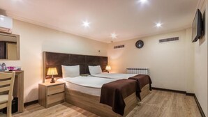 A hotel room with a large bed, bedside tables, a desk, and a TV. - Deluxe İnn Hotel Baku (Baku)