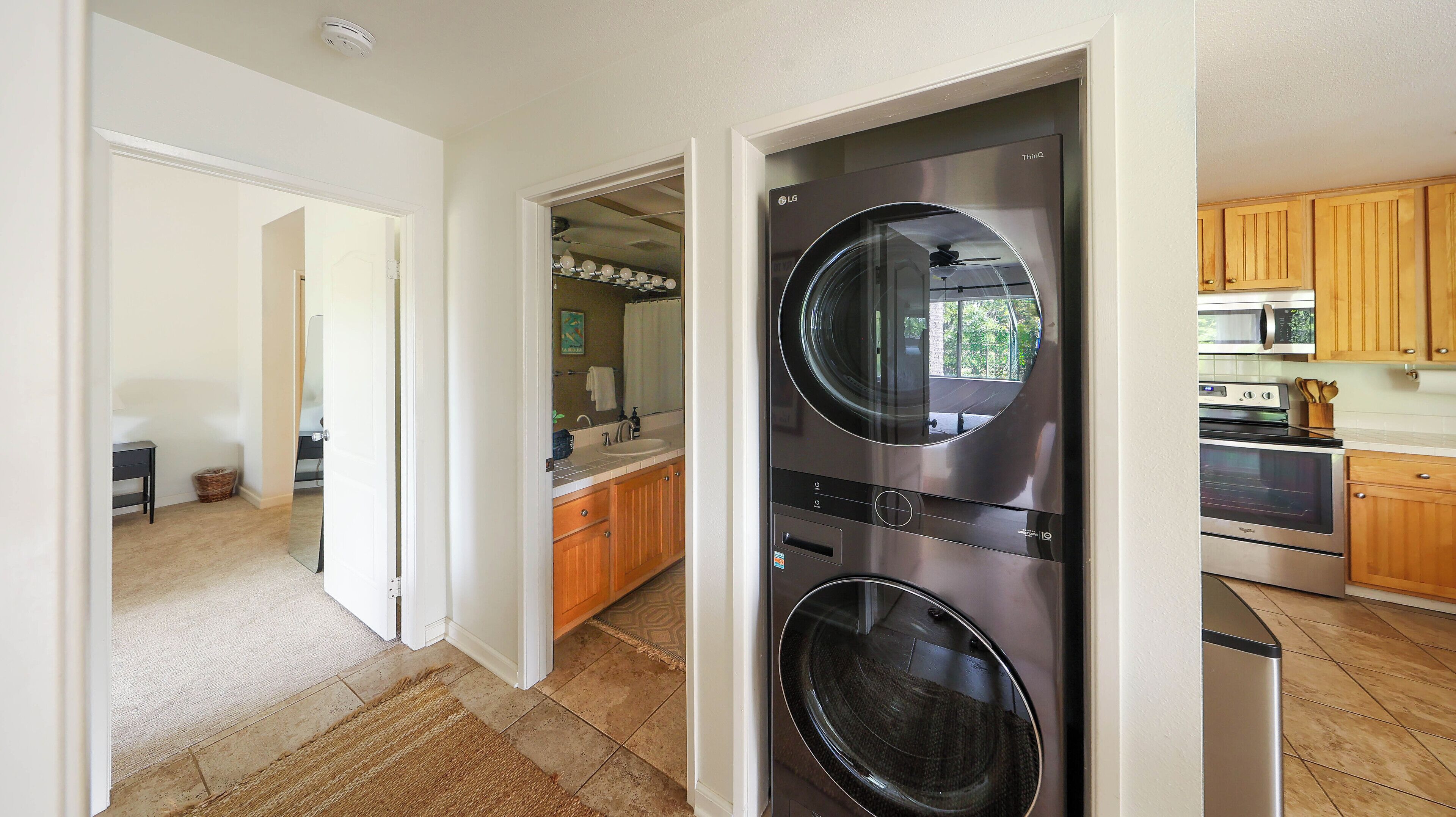 A modern kitchen with stainless steel appliances, wooden cabinets, and a visible laundry area.