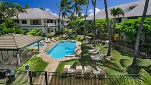 A resort with a swimming pool, lounge chairs, and palm trees.