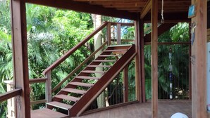 A wooden staircase leading to an upper deck with a table and chairs.