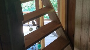 A wooden staircase with a view of greenery outside.