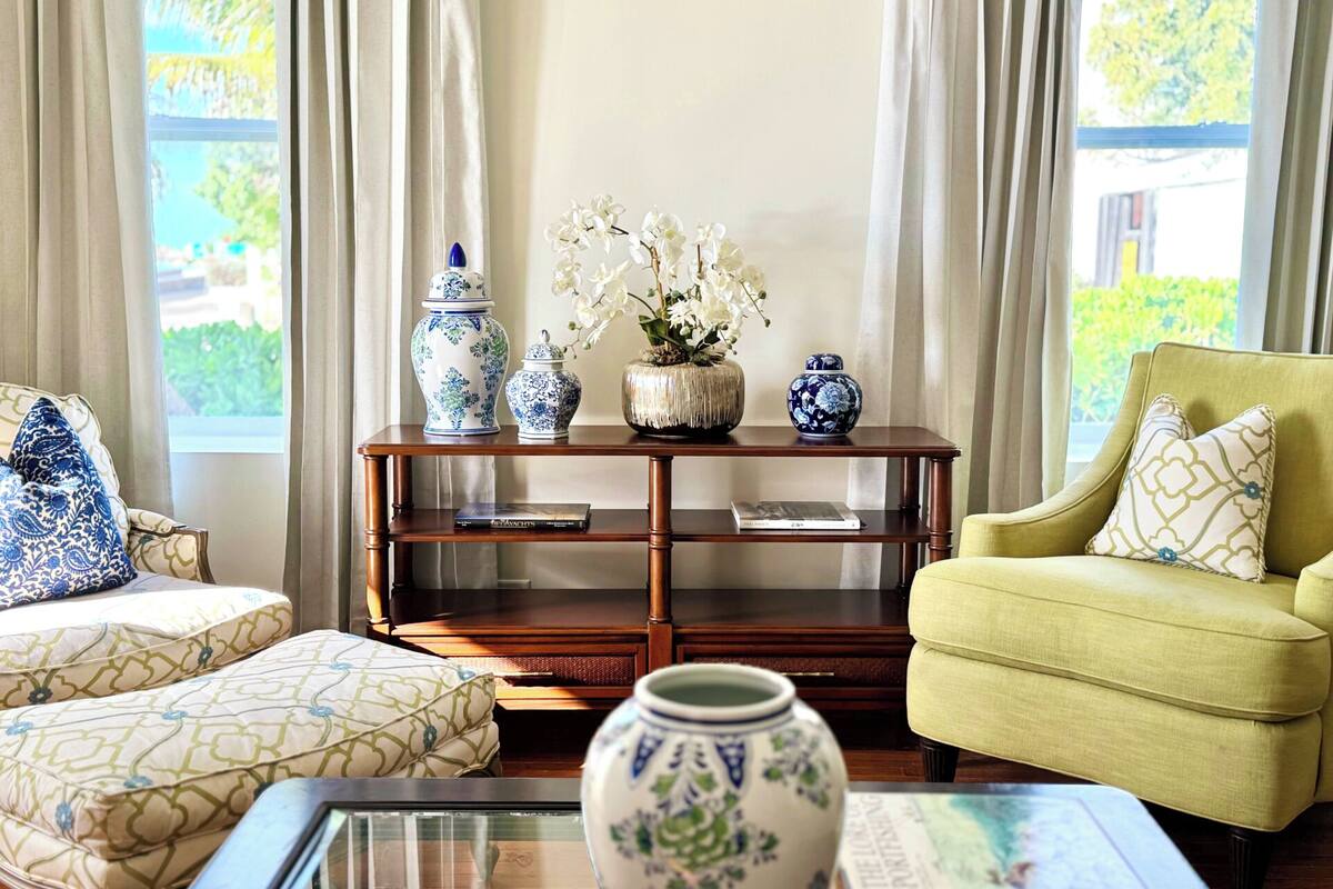 A living room with two patterned sofas, a wooden coffee table, and a side table with decorative vases and books.