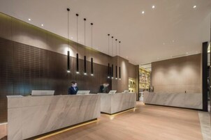 Una moderna zona de recepción con mostradores de mármol e iluminación colgante.