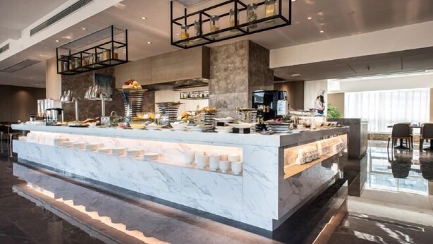 A modern kitchen with marble countertops, a central island, and hanging shelves. - Jade Crystal Hotel (Taizhou)