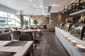 A modern restaurant with a long counter, multiple seating areas, and a buffet setup. - Jade Crystal Hotel (Taizhou)
