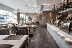Un restaurante moderno con una barra larga, varias zonas de estar y una disposición tipo bufé.