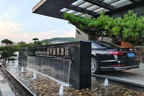 A black car parked in front of a building with a water feature and a sign. - Jade Crystal Hotel (Taizhou)