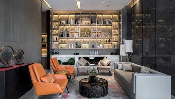 Un salon moderne avec des canapés en cuir, une table basse et une bibliothèque remplie de livres et d’objets décoratifs.