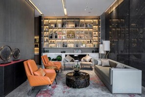 A modern living room with leather sofas, a coffee table, and a bookshelf filled with books and decorative items. - Jade Crystal Hotel (Taizhou)