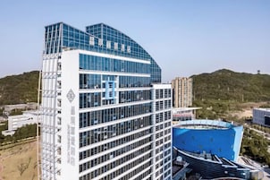 Un hotel de varios pisos con diseño moderno, que destaca por su fachada de vidrio y una estructura de techo curva.