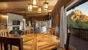 Ein Holzinterieur mit einem runden Esstisch, einem Kamin und Blick auf Berge.