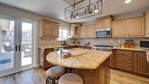 Une cuisine spacieuse dotée d’un grand îlot central, de meubles en bois et d’appareils électroménagers modernes.