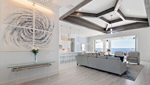 Un salon moderne avec un canapé gris, une table basse en verre et un grand tableau abstrait accroché au mur.