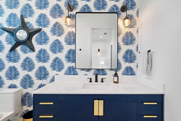 Un baño con una lámpara en forma de estrella, un espejo y un lavabo con un armario azul.