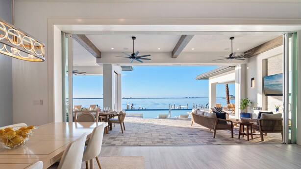 Une salle à manger spacieuse avec vue sur la mer, dotée d’un ventilateur de plafond et présentant un aménagement intérieur moderne.