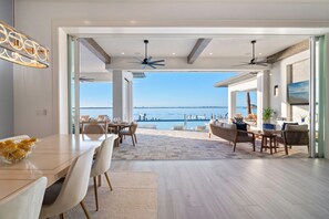 Un comedor amplio con vista al mar, ventilador de techo y un diseño de interiores moderno.