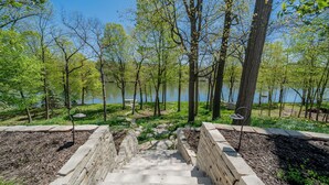 A stone staircase leading to a park with a lake and trees. - Luxurious Riverfront, Indoor Golf, Gym, Nature paradise (Kaukauna)