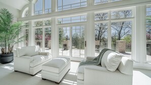 A spacious room with large windows, a white sofa, and a potted plant. - Luxurious Riverfront, Indoor Golf, Gym, Nature paradise (Kaukauna)
