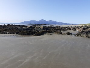 A beach with rocky terrain and a distant mountain range.
