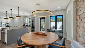 Una cocina moderna con una isla central, iluminación colgante y vistas al exterior a través de grandes ventanales.