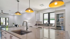Una cocina moderna con una isla central, electrodomésticos de acero inoxidable e iluminación colgante.