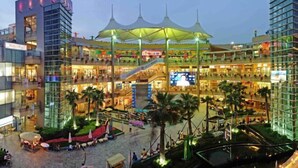 A multi-level shopping mall with a central atrium, escalators, and palm trees. - Shangji Hotel (Shanghai Hongqiao Airport ,West Xianxia Road ) (Shanghai)