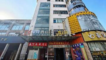 Un edificio de varios pisos con diversos comercios en la planta baja, incluyendo un hotel y un salón de karaoke.