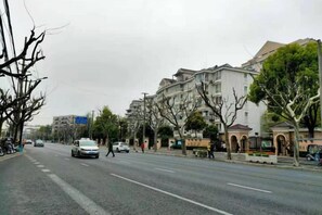 A wide urban street with buildings, trees, and a few vehicles. - Shangji Hotel (Shanghai Hongqiao Airport ,West Xianxia Road ) (Shanghai)
