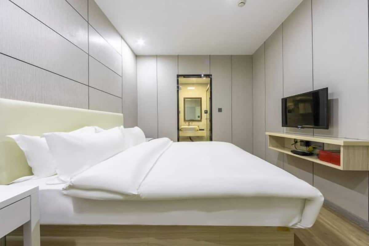 A modern hotel room with a bed, a TV, and a small desk.