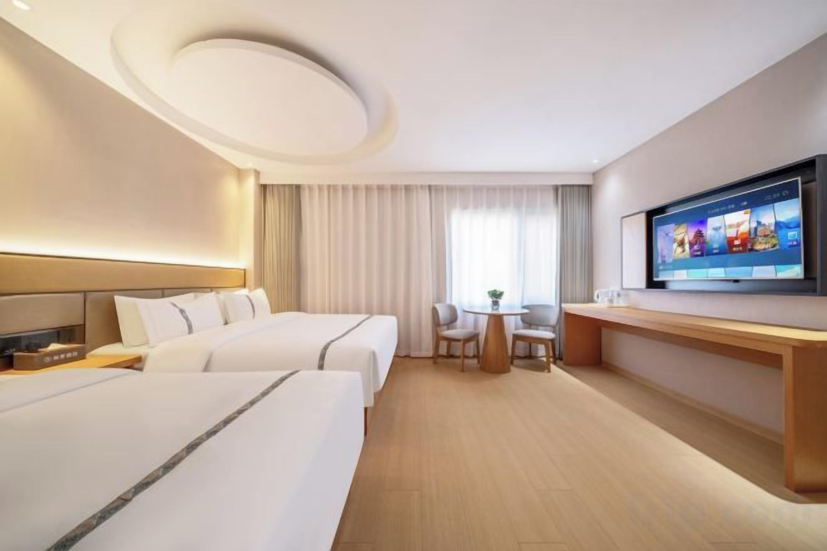 Une chambre d’hôtel avec deux lits, un bureau, une télévision et une fenêtre avec des rideaux.